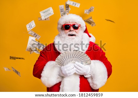 Portrait of his he nice attractive cheerful glad lucky fat overweight bearded Santa holding in hand throwing usd 100 cash interest rate loan isolated bright vivid shine vibrant yellow color background