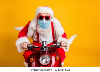 Portrait of his he nice funky hipster grey haired elderly Santa wearing gauze safety mask driving moped fast delivering presents stay home sale isolated over bright vivid yellow color background - Powered by Shutterstock