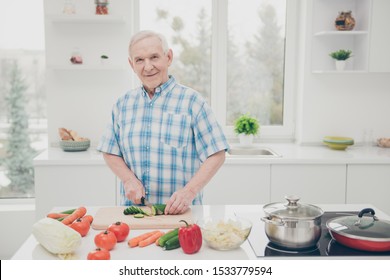 Portrait of his he one single nice attractive lovely cheerful cheery granddad cooking fresh delicious dishes in modern light white interior kitchen indoors
