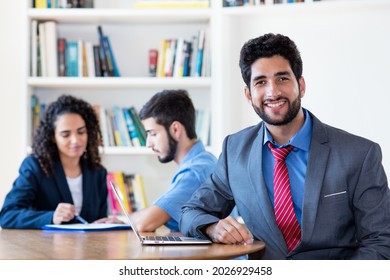 Portrait Of Hispanic Businessman  With Group Of Latin American Business People At Desk At Office