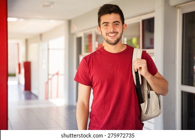 Portrait of a Hispanic college student carrying a backpack and standing in a school hallway