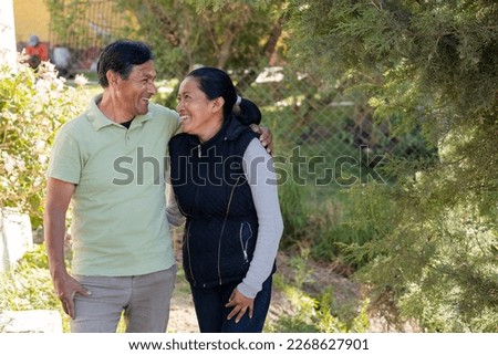 Portrait of hispanic couple hugging while smiling - Senior adult couple enjoying walk in the park - Latin retired adults