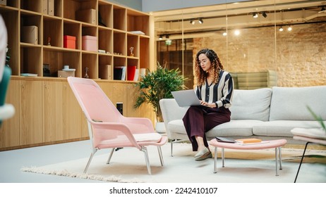 Portrait of Hispanic Creative Young Woman Working on a Laptop in Casual Office. Female Team Lead Smiling While Checking her Team Performance Data. Focused Hard Worker. Wide Shot - Shutterstock ID 2242410107