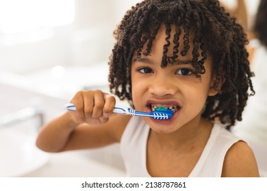 Portrait of hispanic curly haired boy brushing teeth in bathroom at home. unaltered, childhood, hygiene and routine concept. - Shutterstock ID 2138787861