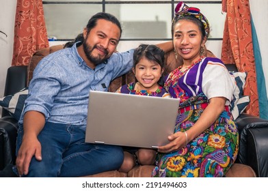 Portrait of a Hispanic family looking at the camera with their little daughter and a computer in their hands. - Powered by Shutterstock