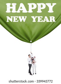 Portrait Of Hispanic Family Standing In Studio And Pulling A Banner New Year