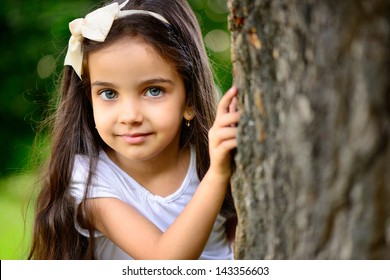 Portrait Of Hispanic Girl With Deep Blue Eyes In Sunny Park