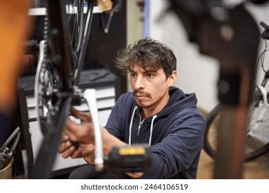 Portrait of an hispanic man focused assembling a bicycle in his bike shop as part of a maintenance service. Composition with the subject framed and selective focus. Real people at work. - Powered by Shutterstock