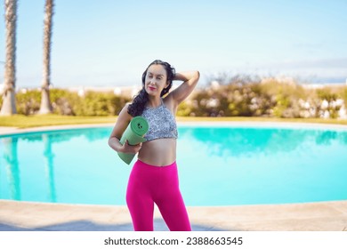 portrait hispanic mid adult woman with yoga mat at poolside - Powered by Shutterstock