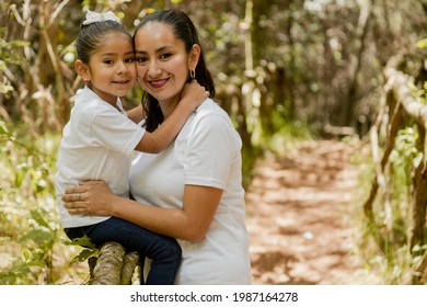 Portrait Of Hispanic Mom Hugging Her Daughter In The Park-loving Mother And Daughter-happy Family Taking A Walk