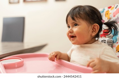 portrait of a Hispanic toddler girl waiting for food on her baby chair, Latin kid before mealtime - Powered by Shutterstock