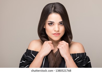 Portrait Of Hispanic Woman Holding Long Straight Hair Over Beige Background