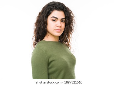 Portrait Of A Hispanic Young Woman In Front Of A White Background With A Serious And Determined Expression In Her Face