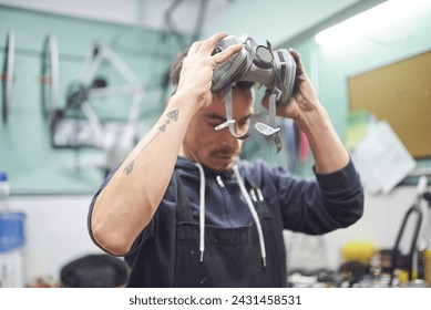 Portrait of an hispanic young worker removing a respiratory protection mask, as he finishes a spray painting job in his workshop. Health protection in industrial work. Real people working. - Powered by Shutterstock