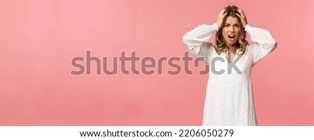 Portrait of hopeless, panicking desperate young blond girl dont know what do, feel alarmed and uneasy, grab head with hands gasping, frowning as looking at something really upsetting