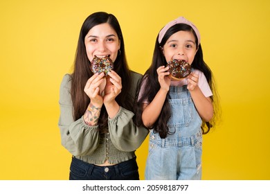 Portrait Of A Hungry Beautiful Mom And Adorable Girl Eating Chocolate Donuts Together 