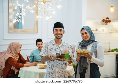 portrait of husband and wife serving food for friend and family for break fasting together during ramadan