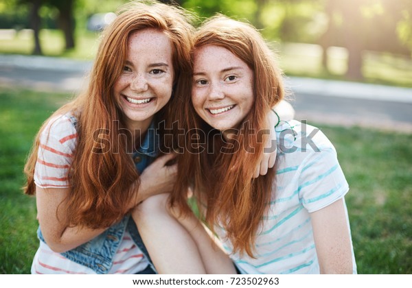 Portrait of identical ginger twin sisters\
smiling and having fun. Red haired rascals taking the best of their\
life. Friendship and youth\
concept.