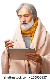 Portrait Of Ill Senior Caucasian Man Covered With Blanket Holding Thermometer And Looking For Doctor Online By Ipad Tablet PC Isolated On White Background