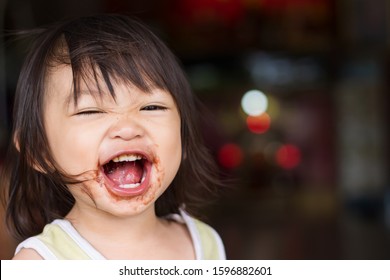 Portrait Image Of 1-2 Yeas Old Baby. Happy Asian Child Girl Eating A Brown Chocolate By Herself. Her Face Messy And Dirty By Food.