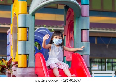 Portrait Image Of 2-3 Yeas Old Baby. Happy Asian Child Girl Smiling And Wearing Fabric Mask,​ She Playing With Slider Bar Toy At The Playground, Social​ Distance,​ Learning And Active Of Kids Concept.