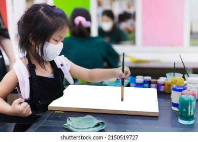 Portrait Image Of 5-6 Years Old Childhood. Kindergarten Child Happy Girl Learning Art Watercolor In Classroom. Kid Wearing White Cloth Face Mask To Prevent Spread Virus And Air Pollution PM2.5. Mockup