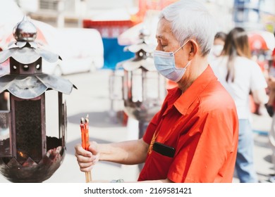 Portrait Image Adult 60 Years Old. Elderly Man Wearing Mask To Protect Against Toxic Dust Pm2.5 Or Virus, Lighting Red Candle. The White-haired Man Is About To Make Wish. People Wear Red Shirts.