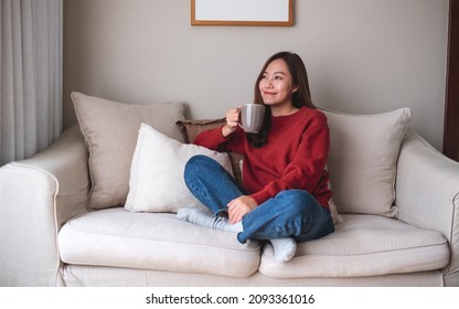 Portrait Image Of A Beautiful Asian Woman Drinking Hot Coffee And Relaxing On A Sofa At Home