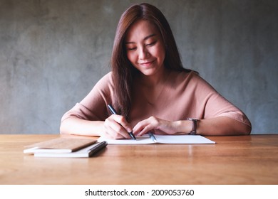 Portrait image of a beautiful young asian woman working and writing on notebook
