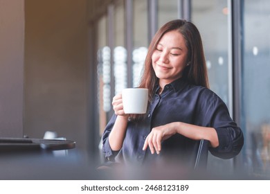 Portrait image of a beautiful young asian woman holding and drinking hot coffee in cafe - Powered by Shutterstock