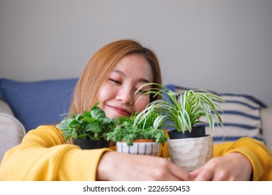 Portrait image of a beautiful young woman holding and hugging houseplants at home - Shutterstock ID 2226550453