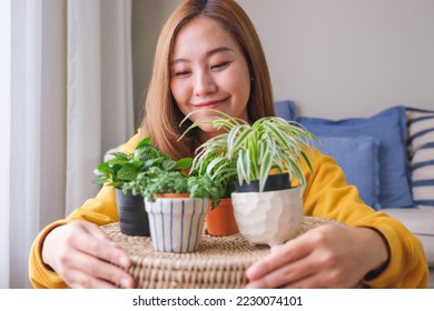 Portrait image of a beautiful young woman holding and hugging houseplants at home - Shutterstock ID 2230074101