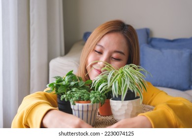 Portrait image of a beautiful young woman holding and hugging houseplants at home - Shutterstock ID 2230074125