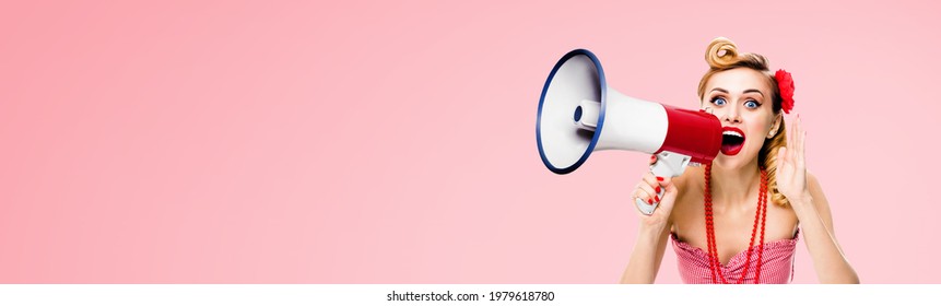 Portrait image of blond haired woman holding megaphone, shout advertising something. Girl in red pin up style clothing, over rose pink color background. Female model in retro vintage studio ad concept