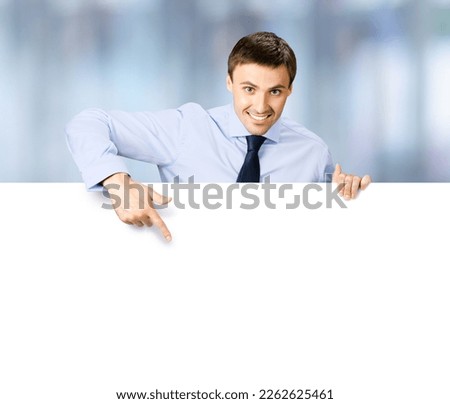 Portrait image of business man professional bank manager in confident cloth. Businessman stand behind, hang over, show point finger empty white banner signboard. Blurred office background