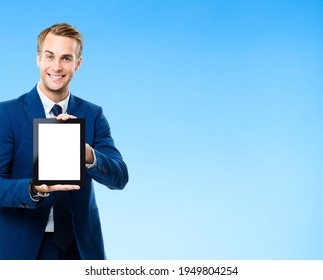 Portrait Image Of Businessman Showing Blank Tablet Pc, With Copy Space Area For Some Text, Advertising Or Slogan, On Blue Background. Smiling Man At Business Studio Concept. IPad Touchpad