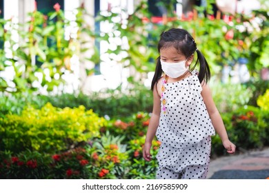 Portrait Image Child 5-6 Years Old. Cute Asian Girl Running In Playground Or Park. Kid Wear White Mask To Prevent PM2.5 Toxic Dust Or Virus. Children With New Way Of Living. Happy Kindergarten Baby.