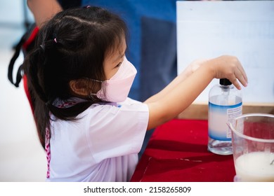 Portrait Image Girl 5-6 Years Old. Kindergarten Child Using Alcohol Gel For Washing Her Hands, After Learning Art With Classroom. Little Kid Wearing Medical Face Mask To Prevent Dust PM2.5 And Virus.