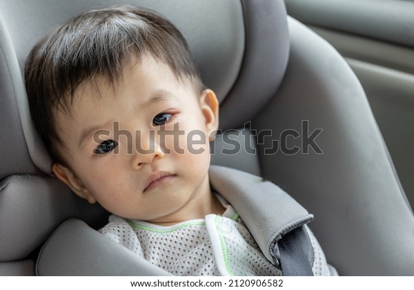Portrait image\
unhappy face of 1-2 years old​ childhood​ child. Face of unhappy\
while sit on safety car\
seat