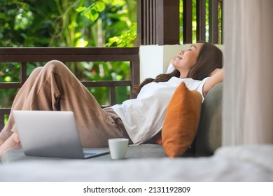 Portrait Image Of A Young Woman Laying Down On Sofa With Laptop Computer And Coffee Cup