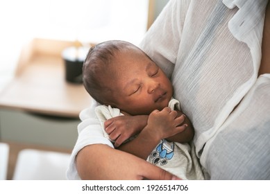 Portrait images of an African, 12-day-old baby newborn son, sleeping with his mother being held, to family and infant newborn concept.