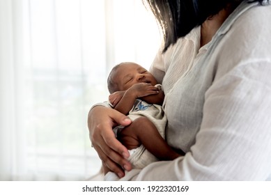 Porträtbilder von halb-afrikanischen halb-thailändischen, 12-tägigen Baby-Neugeborenen-Sohn, schlafend mit seiner Mutter gehalten, zu Familie und Neugeborenen-Konzept.