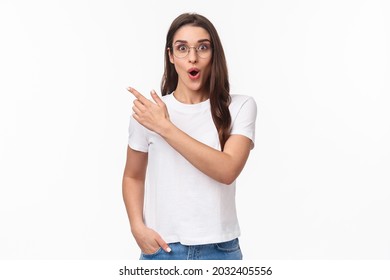 Portrait of impressed and enthusiastic, thrilled brunette female student talking about great opportunity travelling abroad, studying cool university program, pointing finger upper left corner - Shutterstock ID 2032405556