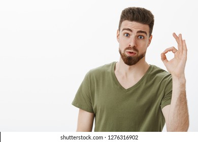 Portrait Of Impressed Guy Checking Out Awesome Idea Of Friend Saying Wow And Not Bad Showing Okay Gesture Raising Eyebrows As Being Amazed With Nice Plan Posing Astonished Over White Background