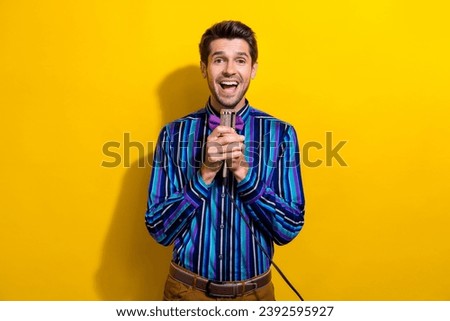 Portrait of impressed guy dressed stylish shirt holding microphone announcing amazing sale isolated on bright yellow color background