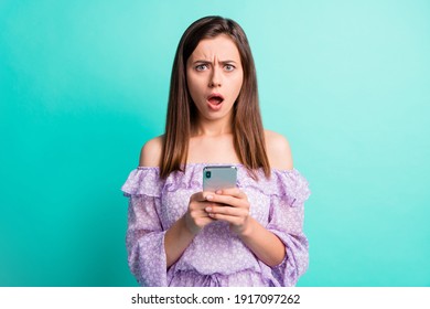 Portrait of impressed sad brunette girl hold telephone open mouth wear purple shirt isolated on blue color background