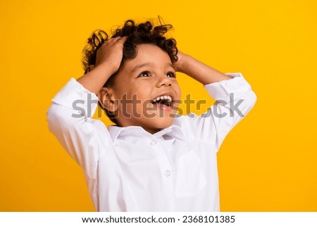 Portrait of impressed schoolboy with wavy hair wear stylish shirt hands on head look empty space sale isolated on yellow color background