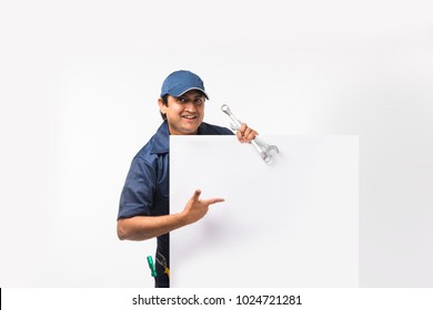 Portrait of indian auto mechanic in blue uniform holding empty banner with spanner. Isolated on white - Powered by Shutterstock