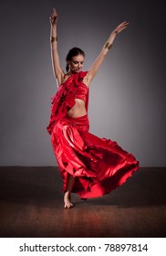 Portrait of Indian dancer in red dress on grey background