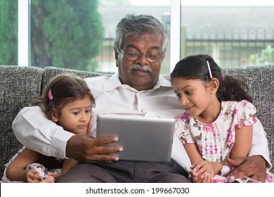 Portrait Indian family at home. Grandparent and grandchildren using digital tablet computer. Asian people living lifestyle.